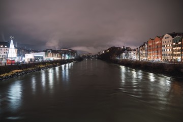 River in the middle of the city with the illuminated buildings on the sides at night