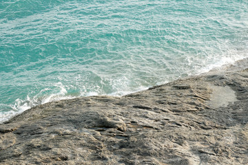 Closeup wave blue sea with rock on the shore 