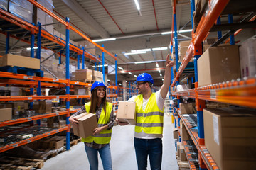 Workers carrying boxes and relocating items in large warehouse center.