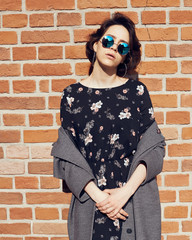 Summer sunny lifestyle fashion portrait of young stylish hipster woman walking on the street