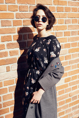 Summer sunny lifestyle fashion portrait of young stylish hipster woman walking on the street