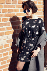 Summer sunny lifestyle fashion portrait of young stylish hipster woman walking on the street