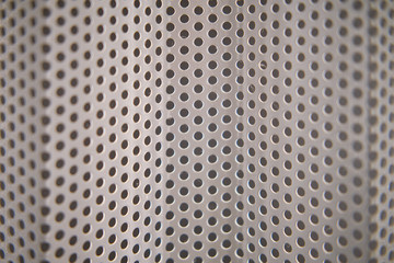 Background in the form of a curved grid with round holes, close-up