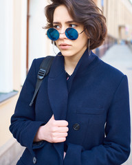 Summer sunny lifestyle fashion portrait of young stylish hipster woman walking on the street
