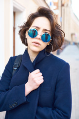 Summer sunny lifestyle fashion portrait of young stylish hipster woman walking on the street
