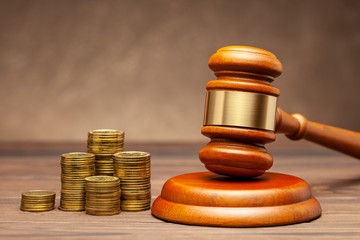 Stack of coins and judge gavel on brown background. The concept of non-payment of taxes.