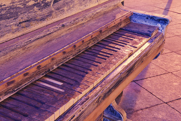 Vintage shabby Grand piano on a night street in the light of lanterns. Dirty piano keys close up