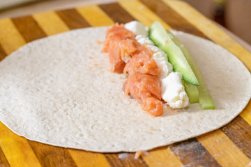 process of cooking tortilla rolls of salmon, tender cheese, lettuce, fresh cucumber close-up