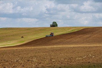 Farmer on a tractor plows the land before sowing with a seedbed cultivator