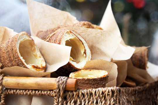 Hot Trdelniks with cinnamon in a wicker basket, on a festive background. Traditional national Czech sweet food Trdelnik, trdlo or kurtoskalacs