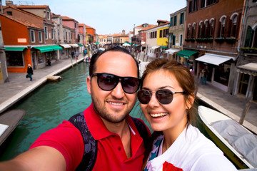 Fototapeta na wymiar Couple traveling in Italy.Happy smiling couple hugging and taking selfie photo in front of Grand Canal in Venice while honeymoon.Happy tourists taking photo of themselves. summer holidays,vacation