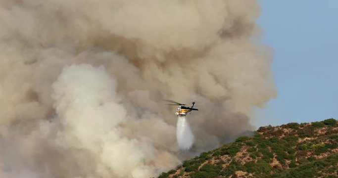 Huge wildfire in Los Angeles county, November 9, 2019. Hollywood hills near the Warner Bros Studio are in fire. Fire department helicopter drops the water on the burning area. Aerial. 4K