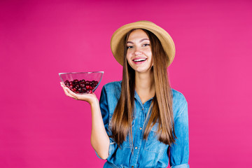 in a girls arm bent in a lock, a vase with berries stands on her palm. background pink