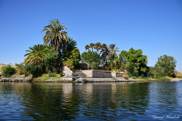 River Nile/ beautiful view for Aswan Egypt and Nubian Egyptian culture. sailing boat sailing in the River Nile and harbor with birds and local houses on the 2 sides 