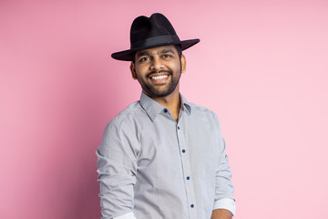 Portrait of handsome Indian guy standing on pink background