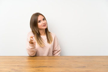 Teenager girl in a table handshaking after good deal