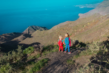 kids-two little girls- travel in mountains near sea, family hiking