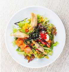 Salmon salad with cream cheese, pickled pumpkin, daikon, beans, tobiko caviar and mango chili sauce. Pan-Asian dish.