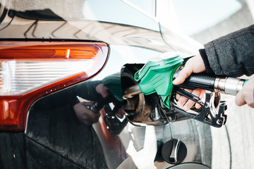 Man pumping petrol at gas station into vehicle. Hand holding a pistol  pump.