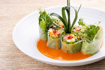 Salmon roll with Philadelphia cheese and pickled pumpkin, in rice paper with daikon and Ponzu sauce. Pan-Asian dish.