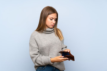 Naklejka premium Teenager girl with sweater over isolated blue background holding a wallet