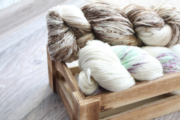 Fototapeta na wymiar Two skeins of multicolored yarn in a wooden box