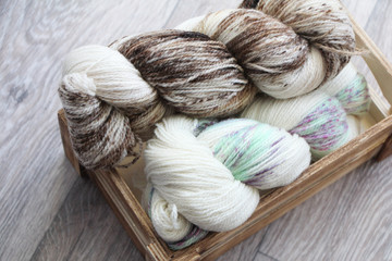 Two skeins of multicolored yarn in a wooden box