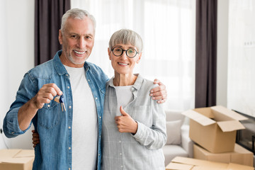 smiling man holding keys and woman showing like in new house
