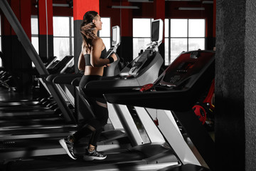 Fototapeta na wymiar Young woman working out on treadmill in modern gym