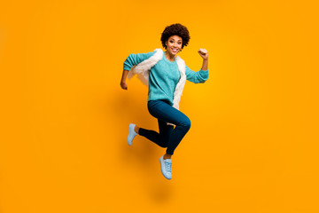 Full size photo of crazy funny funky afro american girl jump run hurry wear white turquoise sweater autumn blue stylish trendy outfit isolated over bright yellow color background