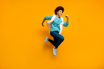 Fototapeta na wymiar Full length photo of crazy beautiful afro american girl jump run discounts wear white teal sweater blue pants stylish trendy trousers sneakers isolated over yellow shine color background