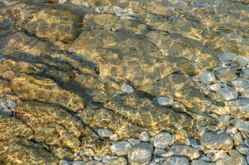 Abstract background texture, Colorful sea stones in water. Wonderful natural background. Clear crystal shallow blue sea water and rocky seabed background, banner.