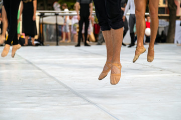 Ballet dancers practicing performance outdoors. Close up of ballerina feet wearing slippers practice moves in ballet class outside