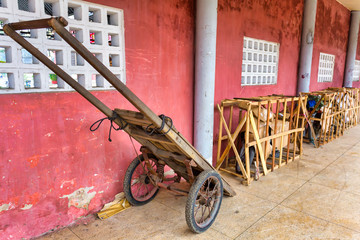 Fototapeta premium Vietnamese motorbike transport service. Bikes are fixed in wooden frames covered with cardboard, wheelbarrow on the foreground. Hue train station, Vietnam