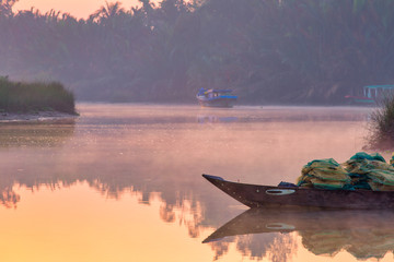 Vietnamese misty river with fishing boats and nets. Hoi An neighborhood, at sunrise.