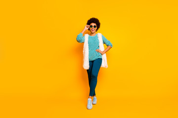 Full size photo of cute positive funky afro american girl enjoy autumn holiday touch spectacles wear white stylish trendy waistcoat blue pants isolated bright color background