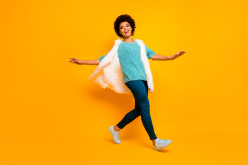 Full length photo of cheerful funky afro american girl relax rest enjoy fun autumn holiday go walk wear good look vest teal sweater bright sneakers isolated shine color background