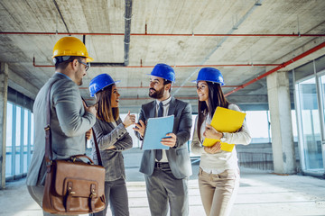 Small group of young hardworking highly motivated architects standing inside of building in...