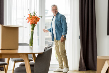 handsome mature man in shirt standing in new house