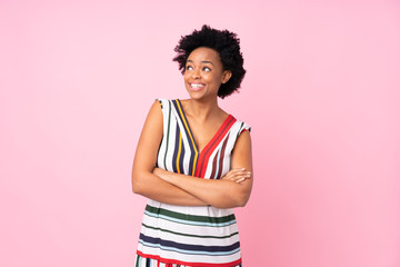 African american woman over isolated pink background looking up while smiling