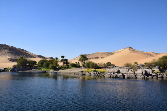 River Nile/ beautiful view for Aswan Egypt and Nubian Egyptian culture. sailing boat sailing in the River Nile and harbor with birds and local houses on the 2 sides 
