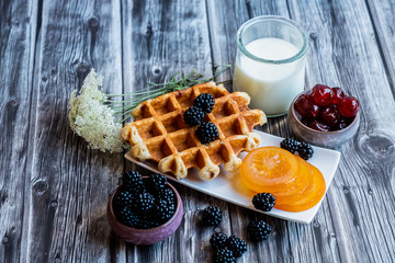 Petit déjeuner sain avec lait gaufre mûres du jardin et fruits confits	