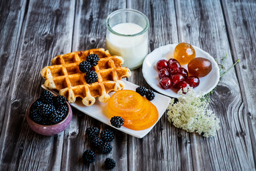 Petit déjeuner sain avec lait gaufre mûres du jardin et fruits confits	