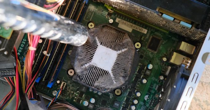 Vacuuming dust from a heatsink on top of a CPU, inside a computer case, using a small vacuum tube. PC maintenance concept.