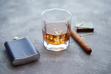 Glass of whiskey with ice, big cuban cigar, matches and hip flask