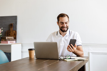 Handsome young bearded man sitting at the table at home