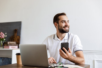 Handsome young bearded man sitting at the table at home