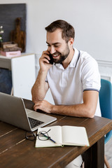 Handsome young bearded man sitting at the table at home