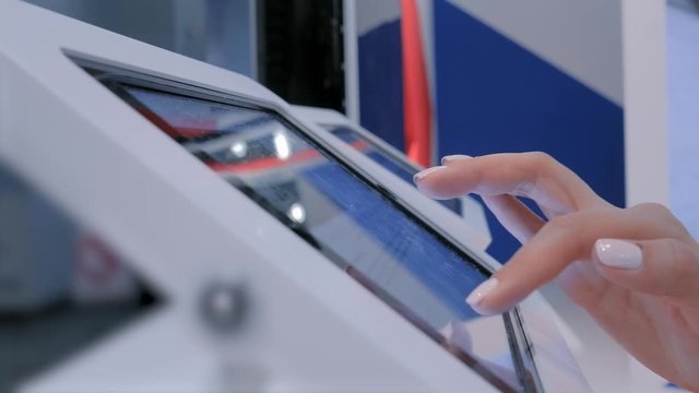 Woman Hand Using Touchscreen Display Of Interactive Floor Standing White Tablet Kiosk At Exhibition Or Museum - Side Close Up View. Futuristic, Education, Entertainment, Learning, Technology Concept