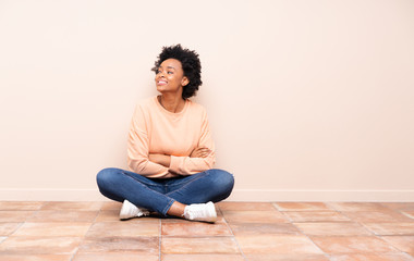 African american woman sitting on the floor with arms crossed and happy